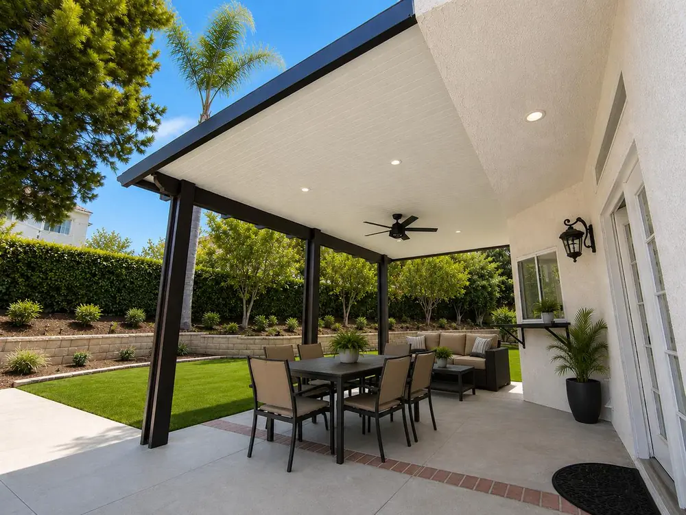 Bronze insulated aluminum patio cover over a dining set beside a manicured lawn