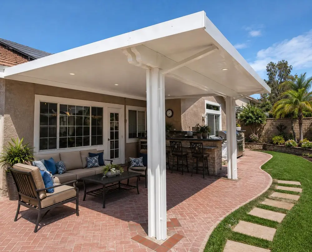 White wood-grain aluminum solid patio cover over an outdoor kitchen and brick patio