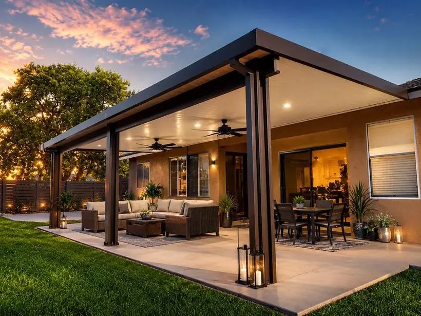 Wood-grain aluminum patio cover over an outdoor living space at sunset