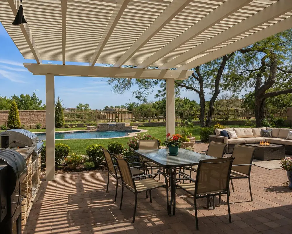 Almond open-lattice aluminum patio cover casting striped shade over a poolside dining set
