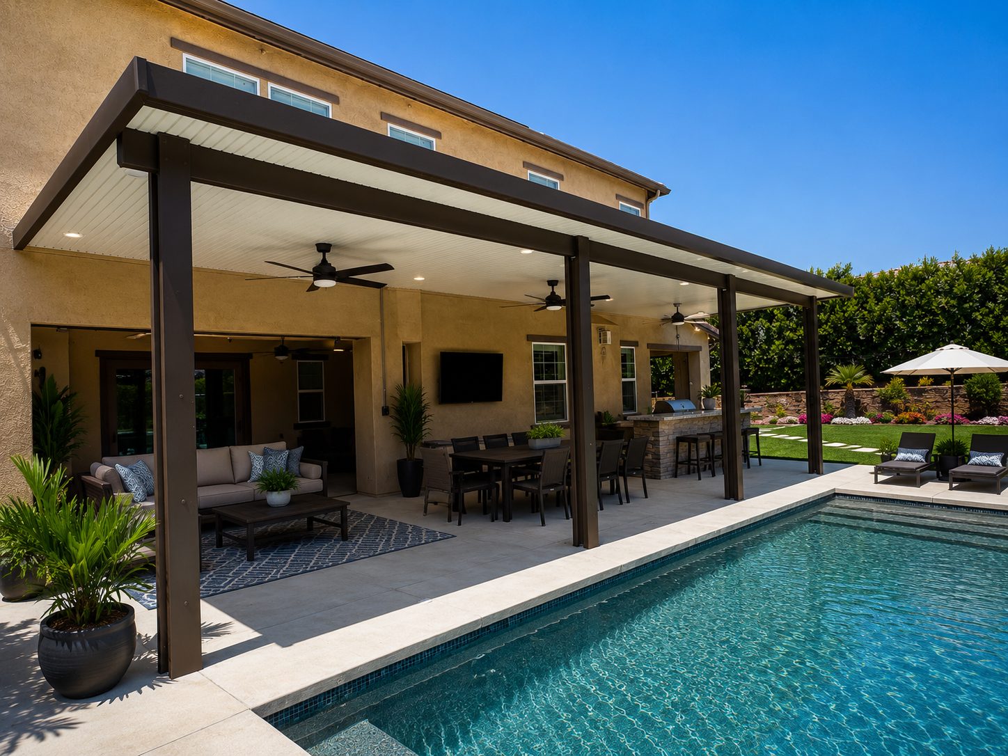 Attached solid-roof wood-grain aluminum patio cover with recessed lighting and ceiling fans shading a poolside patio
