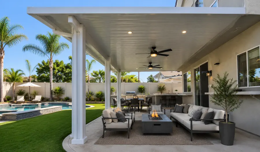White insulated aluminum patio cover over a poolside fire-pit lounge with palm trees